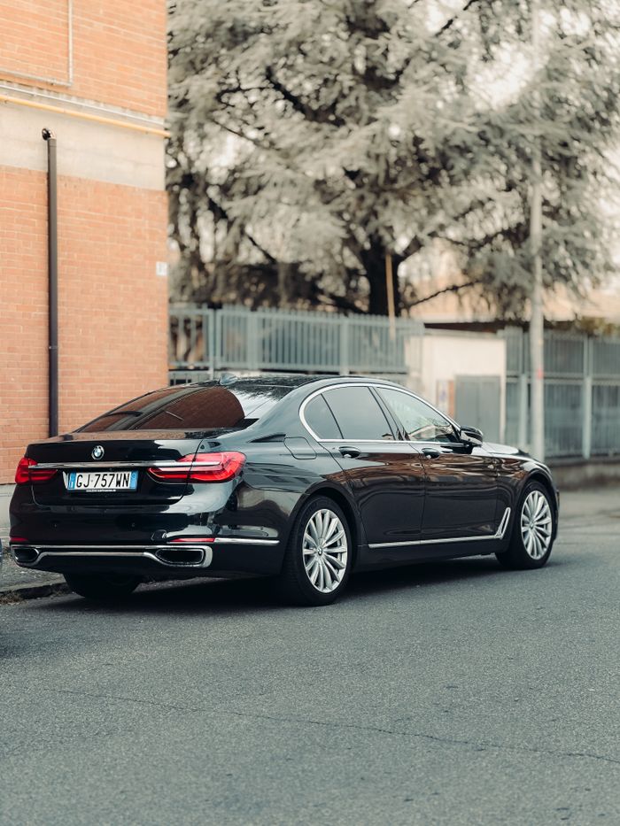 services-04 Elegant black luxury car parked on a city street surrounded by brick and trees.