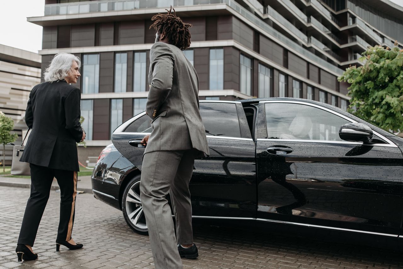 The Art of Drawing Readers In: Your attractive post title goes here Business professionals exiting luxury car near modern building in city setting.